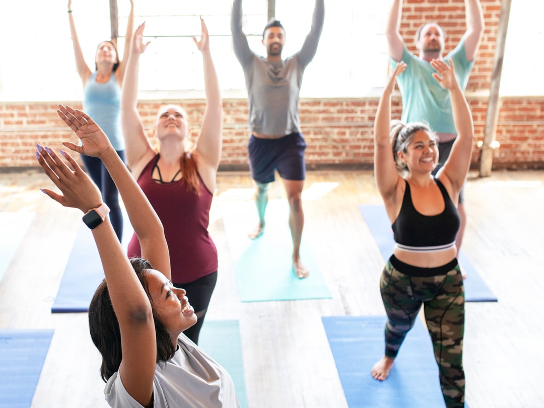 happy group of people doing yoga in hot fitness studio